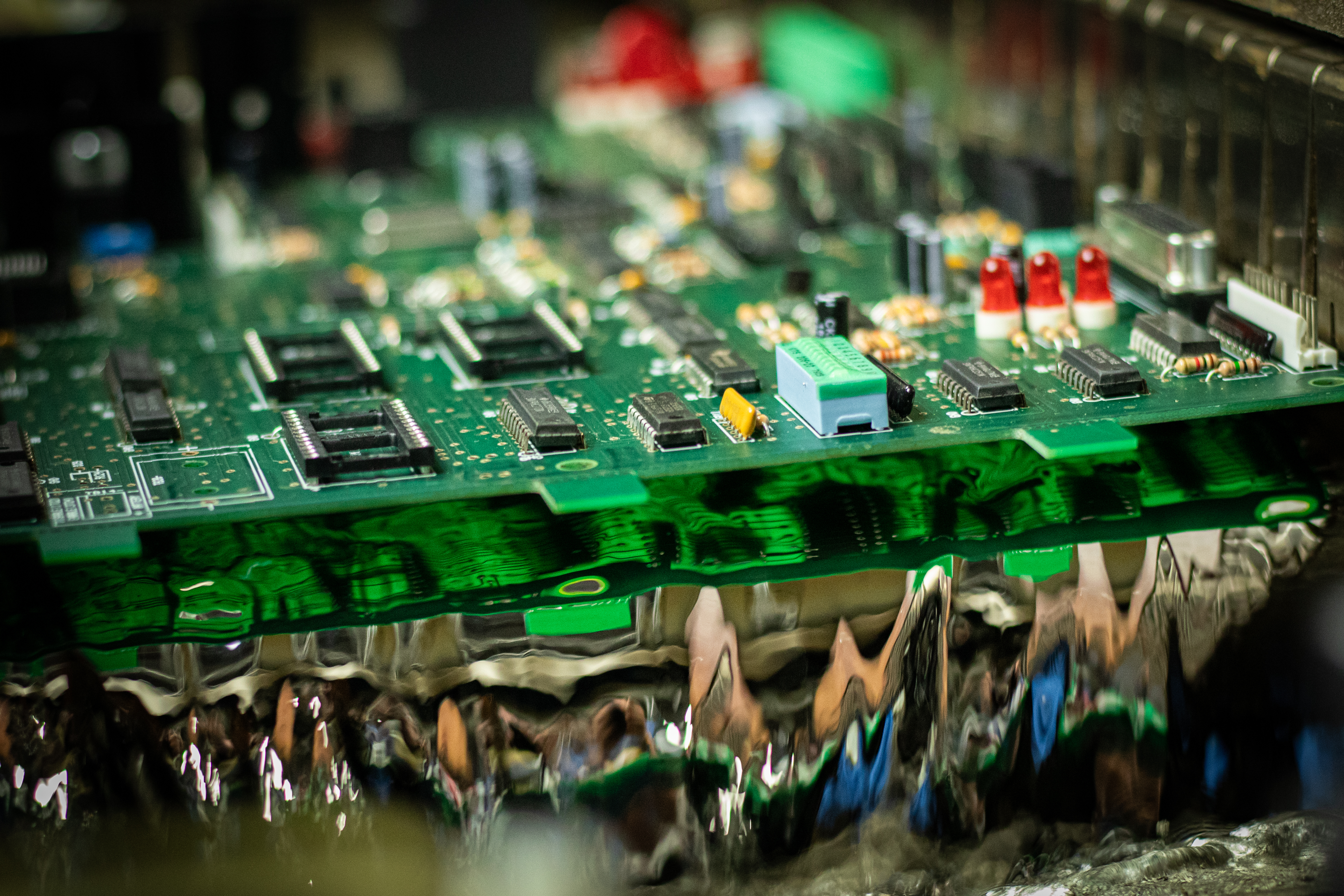 Populated circuit board passing through molten solder in a wave soldering machine during PCB assembly at EverTech